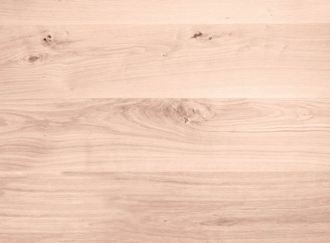 Wide-plank maple hardwood flooring in a sun-filled open-plan living room, showing the grain variation between select and character grade boards